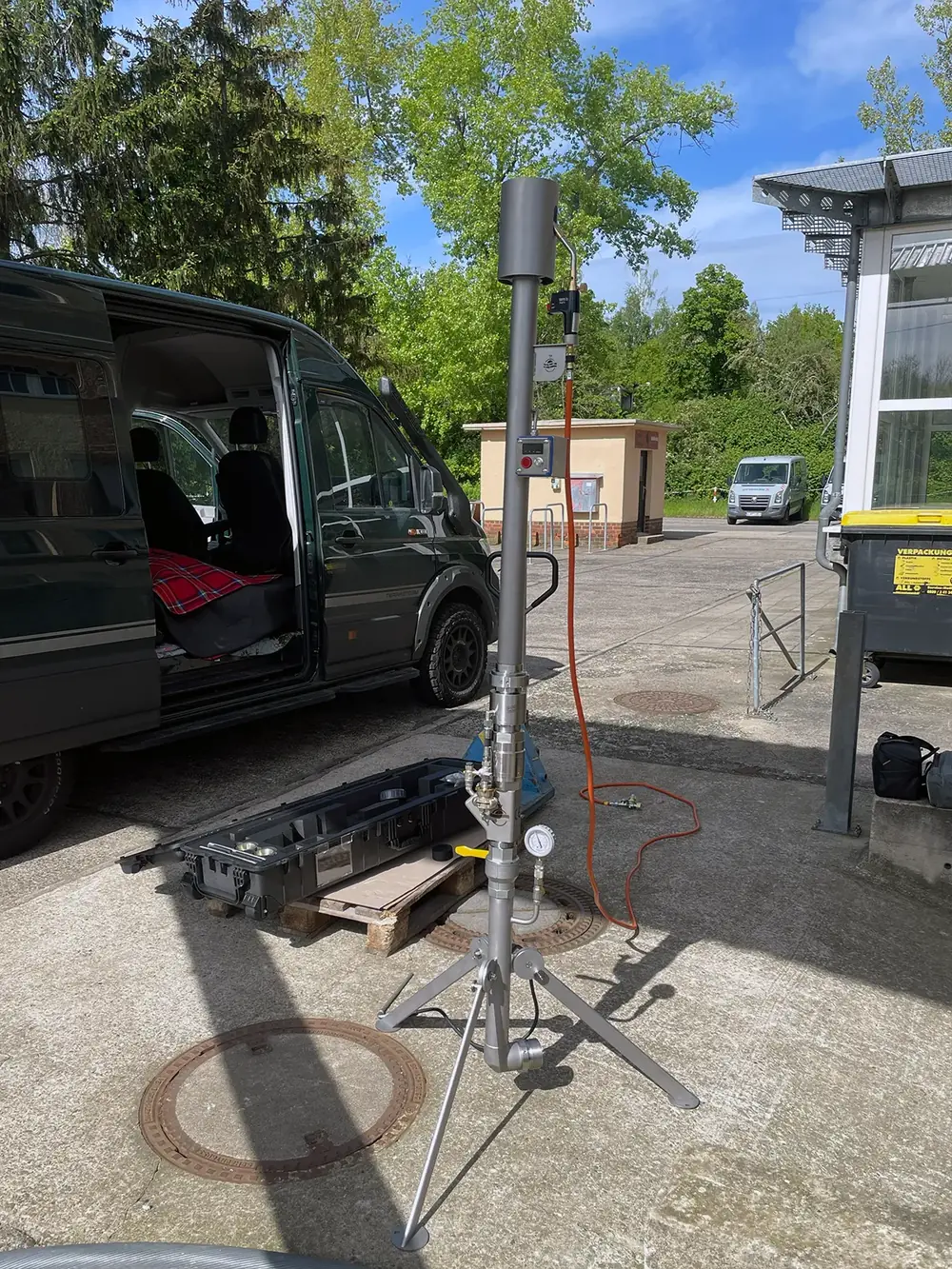 Gasfackel auf dem Stativ vor einer Gasübergabestation, daneben der geöffnete Transporter mit der Ausrüstung.