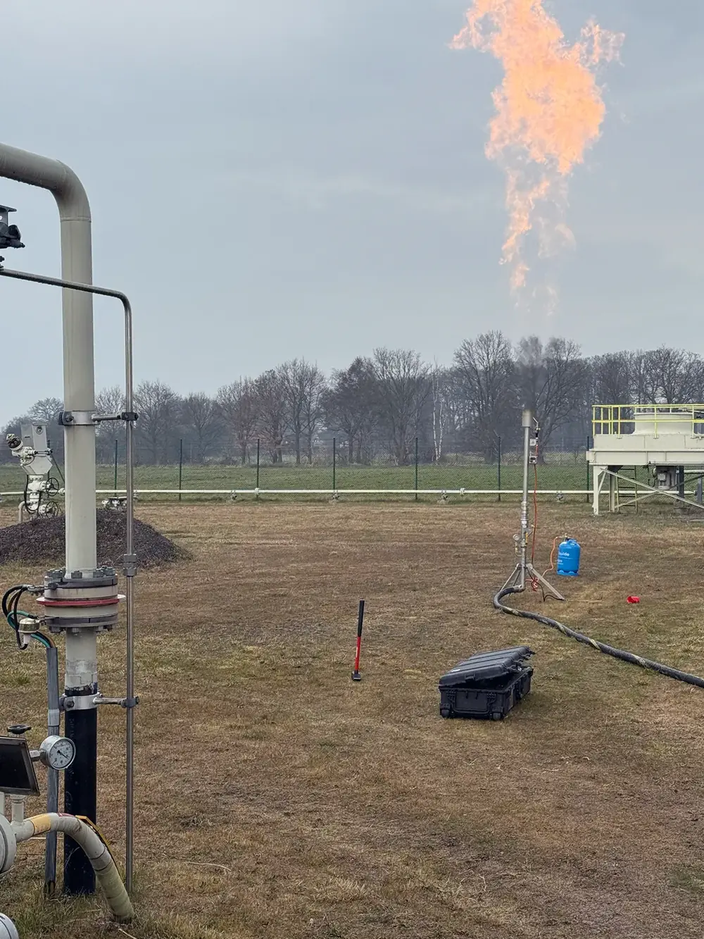 Gasfackel auf einer Wiese neben einer Rohrleitungsanlage.