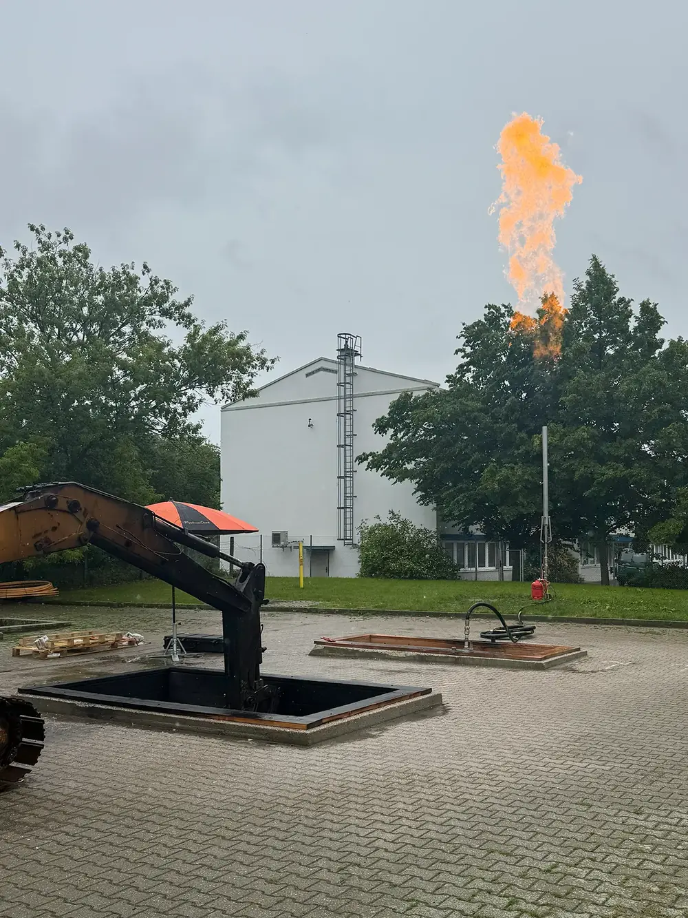 Gasfackel an einer offenen Baugrube, daneben ein Bagger.