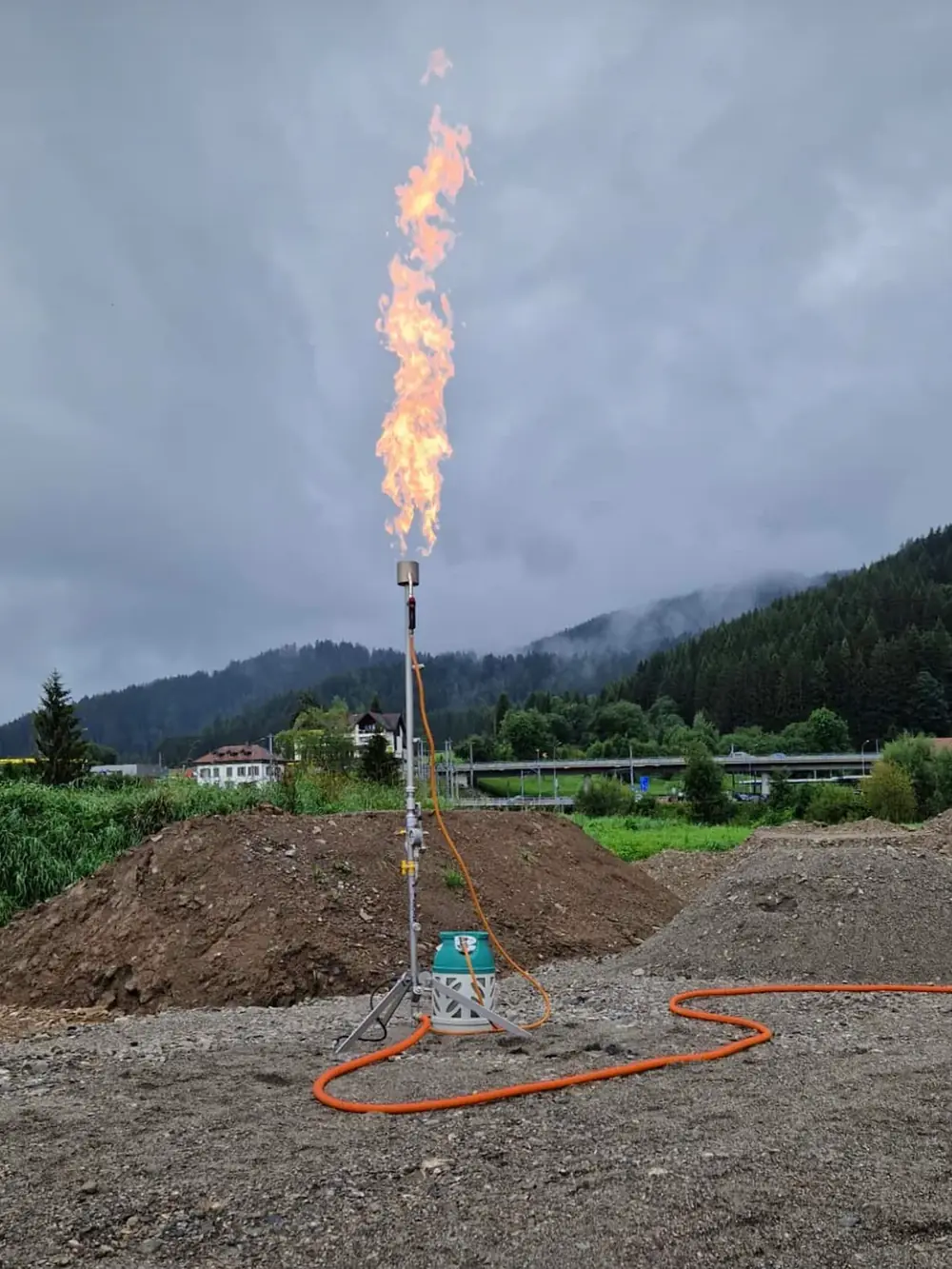 Gasfackel auf einer Erdbaustelle vor bergiger Kulisse.